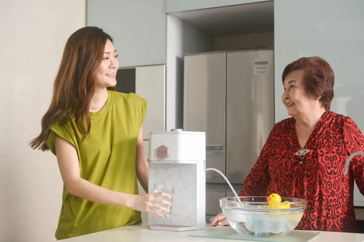 A woman chatting with her mother in the kitchen, holding a glass of water from their AOX dispenser