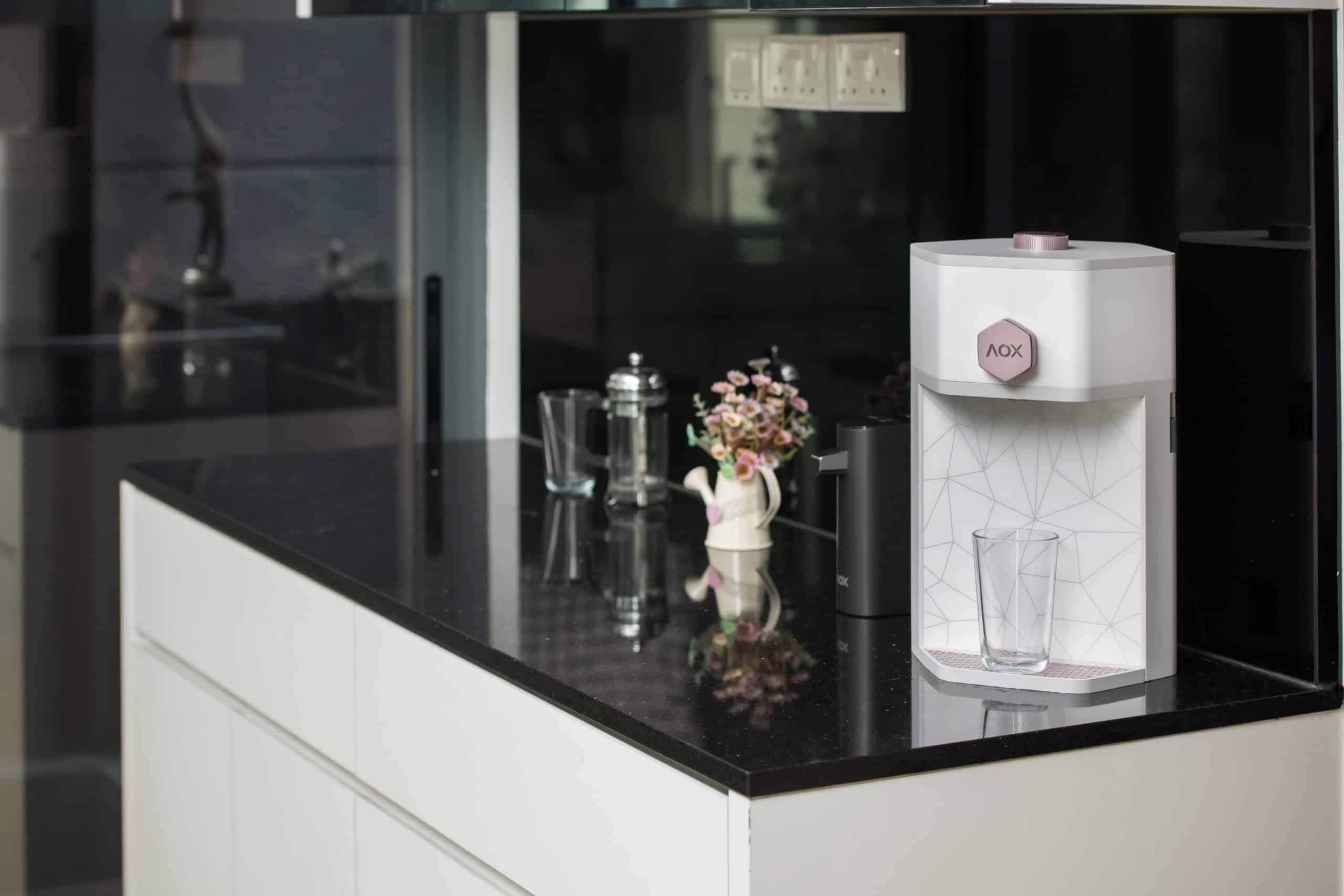 AOX Compac O2+ water dispenser elegantly placed in a modern kitchen with a glass and floral decor.